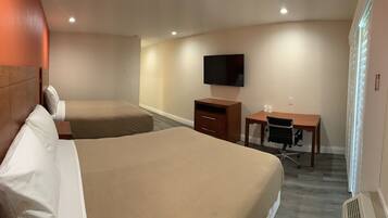 A hotel room with two beds, a desk, a chair, a television, and a window with blinds.