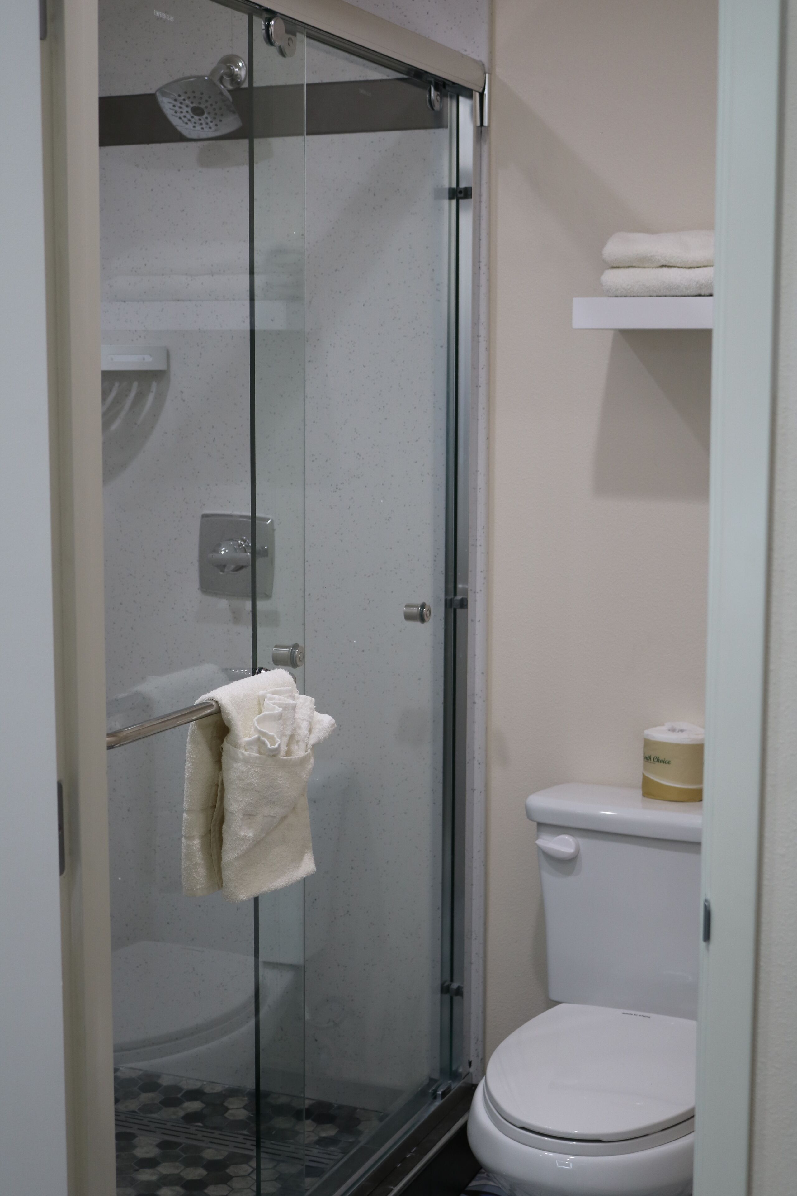 A glass-enclosed shower stall with a towel hanging on the door handle.