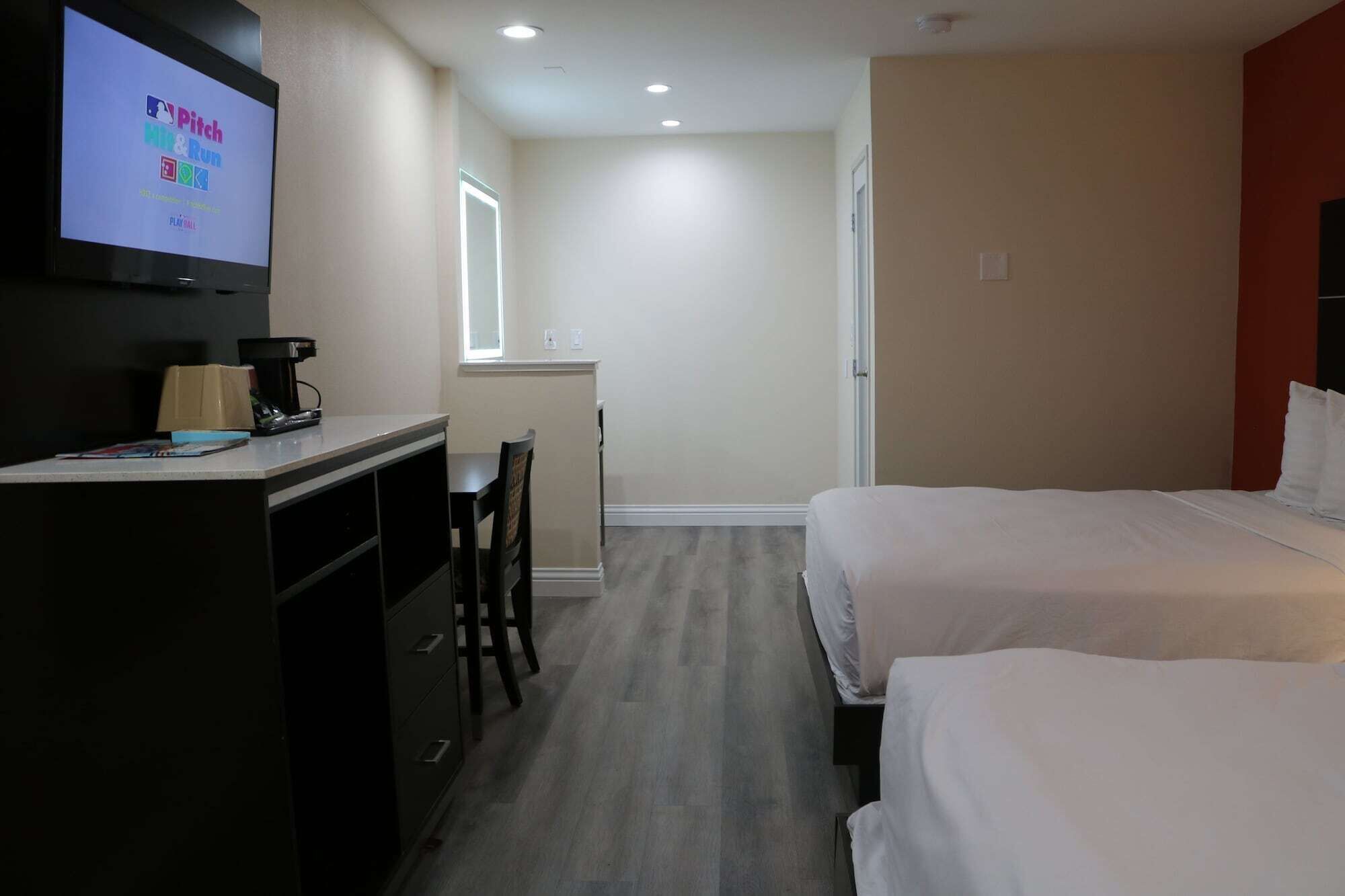 A hotel room with a desk, chair, and two beds.