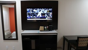 A hotel room with a flat-screen TV mounted on the wall, a desk with a chair, and a small coffee maker. - Motel 6 Vallejo, CA – Napa Valley (Vallejo)