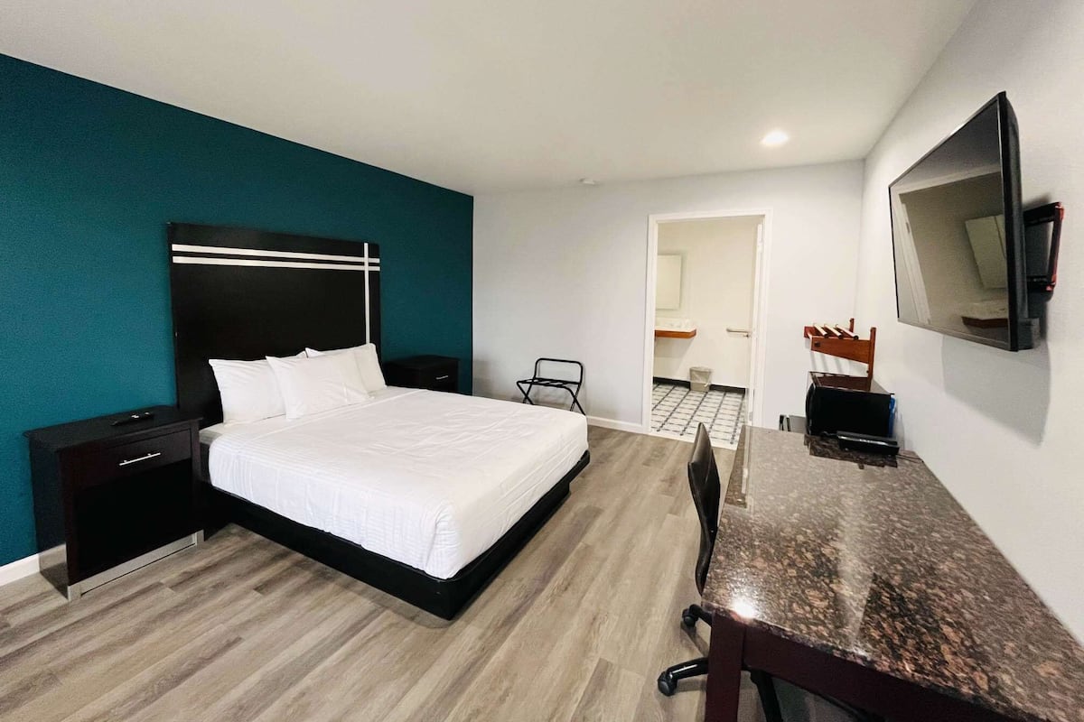 Una habitación de hotel moderna con una cama grande, un escritorio y una televisión montada en la pared.