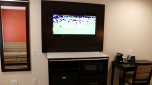 A room with a television mounted on the wall, a small desk with a chair, and a microwave. - Motel 6 Vallejo, CA – Napa Valley (Vallejo)