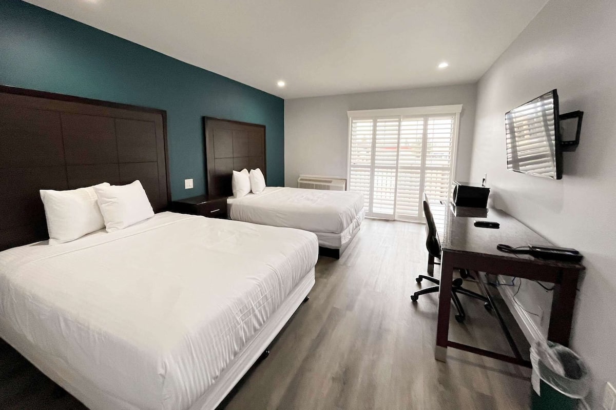 Una habitación de hotel con dos camas, un escritorio y una silla.