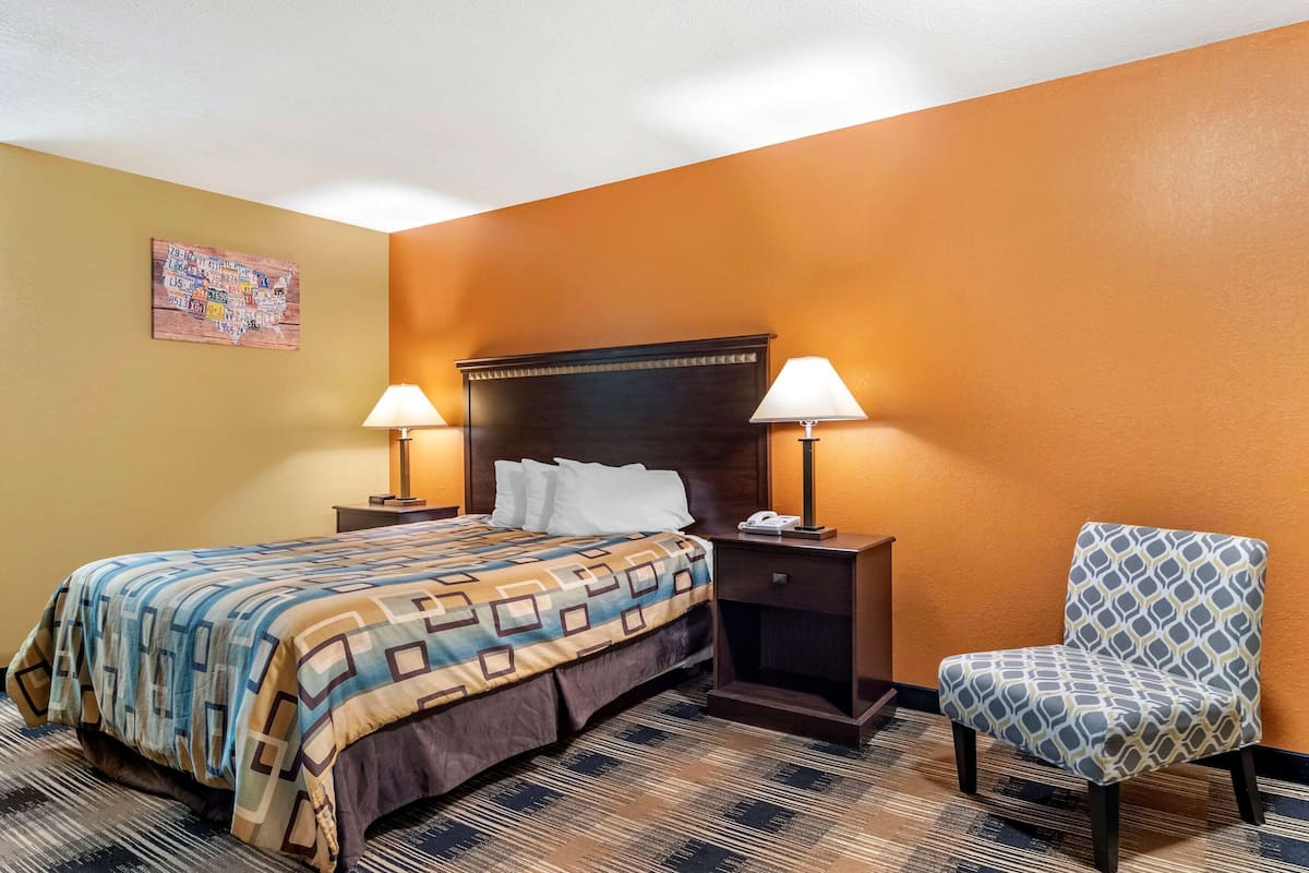 Una habitación de hotel con una cama, dos lámparas de noche, una silla y un mapa mural.