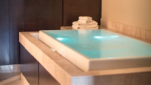 A modern spa area with a rectangular hot tub, dark wooden panels, and a framed artwork on the wall. - Hotel Le Bonne Entente (Québec City)