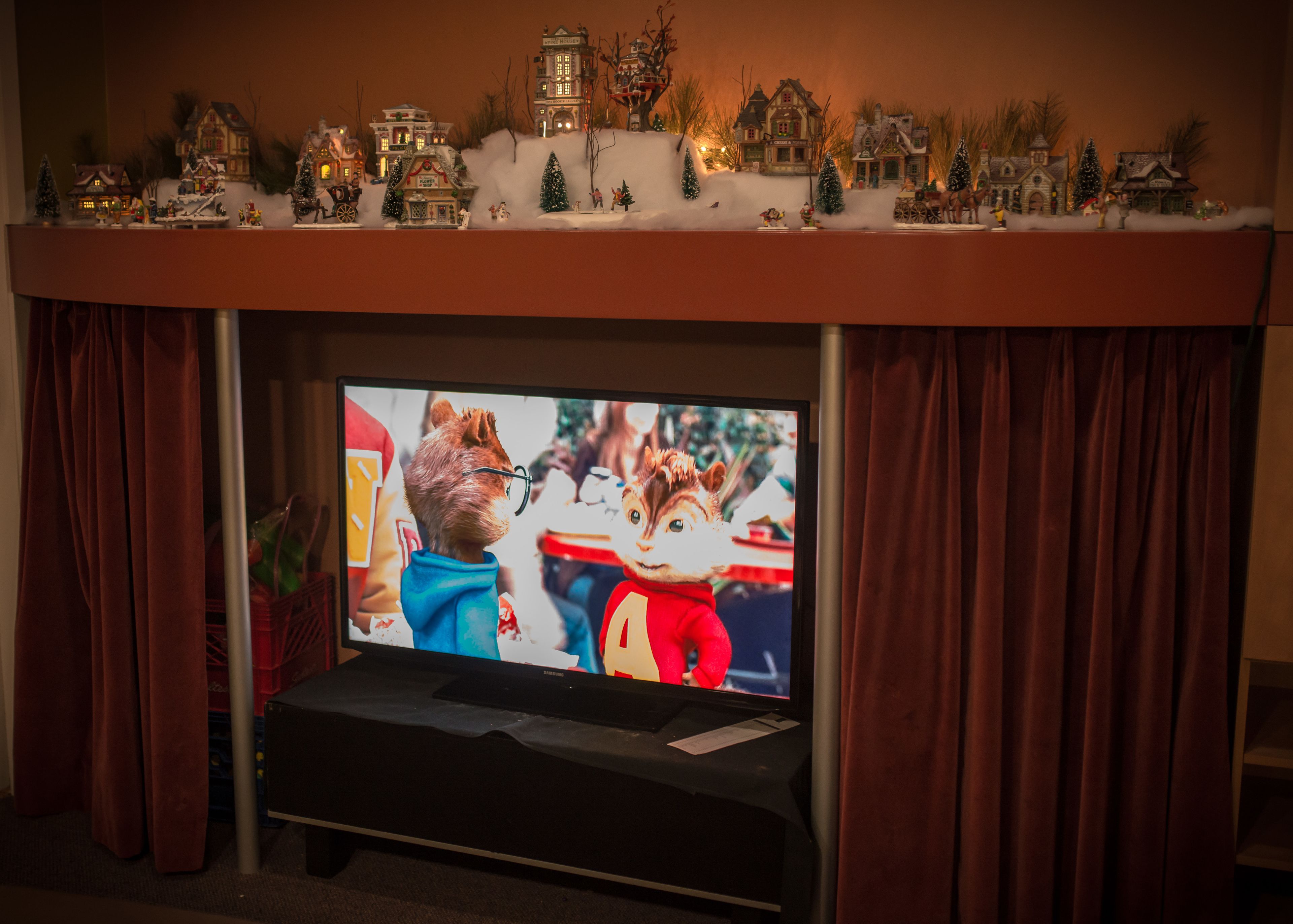 A television screen displaying animated characters, with a Christmas-themed display above it.