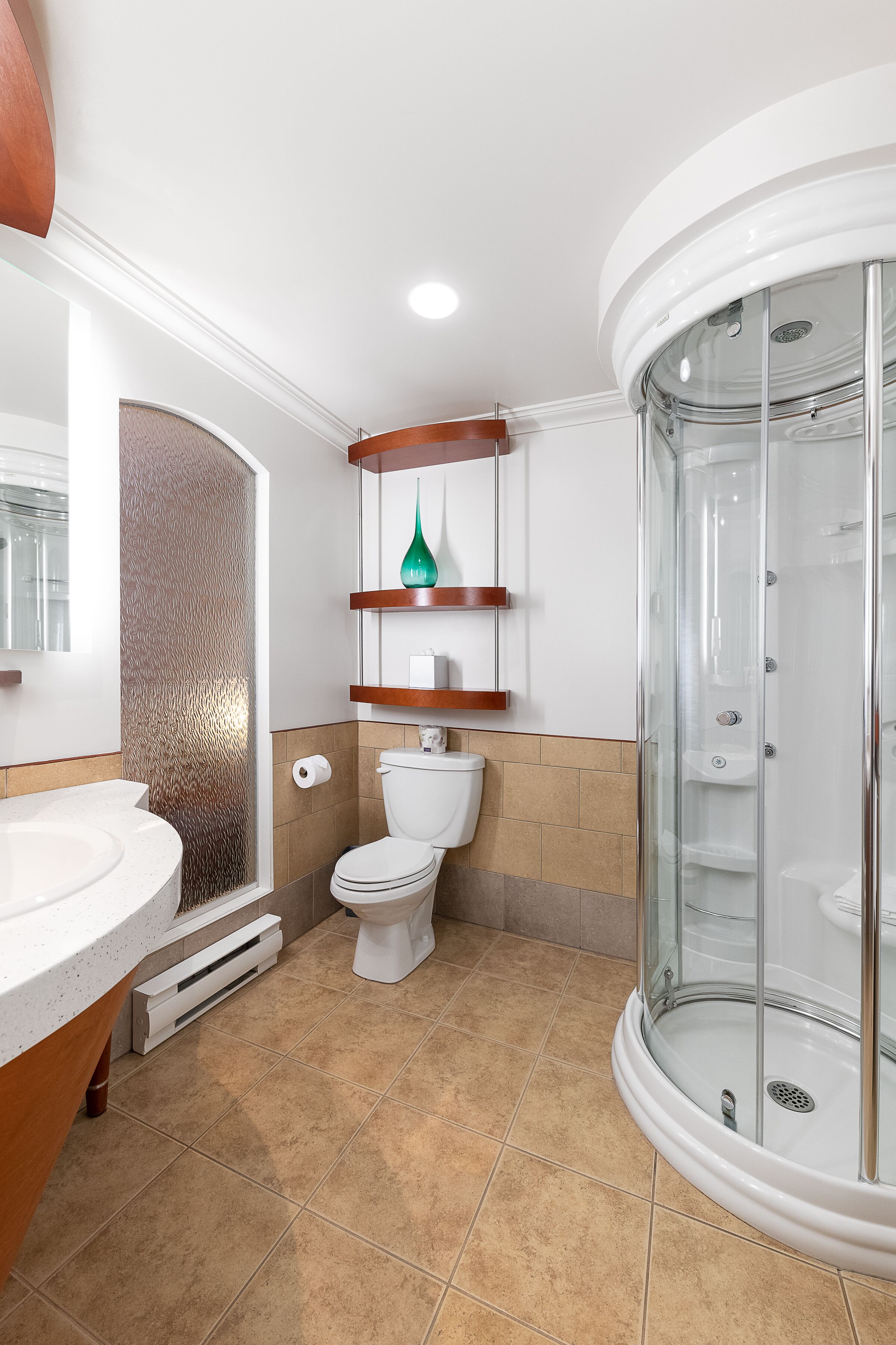 A bathroom with a glass-enclosed shower, a white sink, and a toilet.
