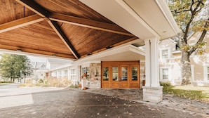 A covered outdoor area with a brick floor, wooden beams, and a stone column. - Hotel Le Bonne Entente (Québec City)