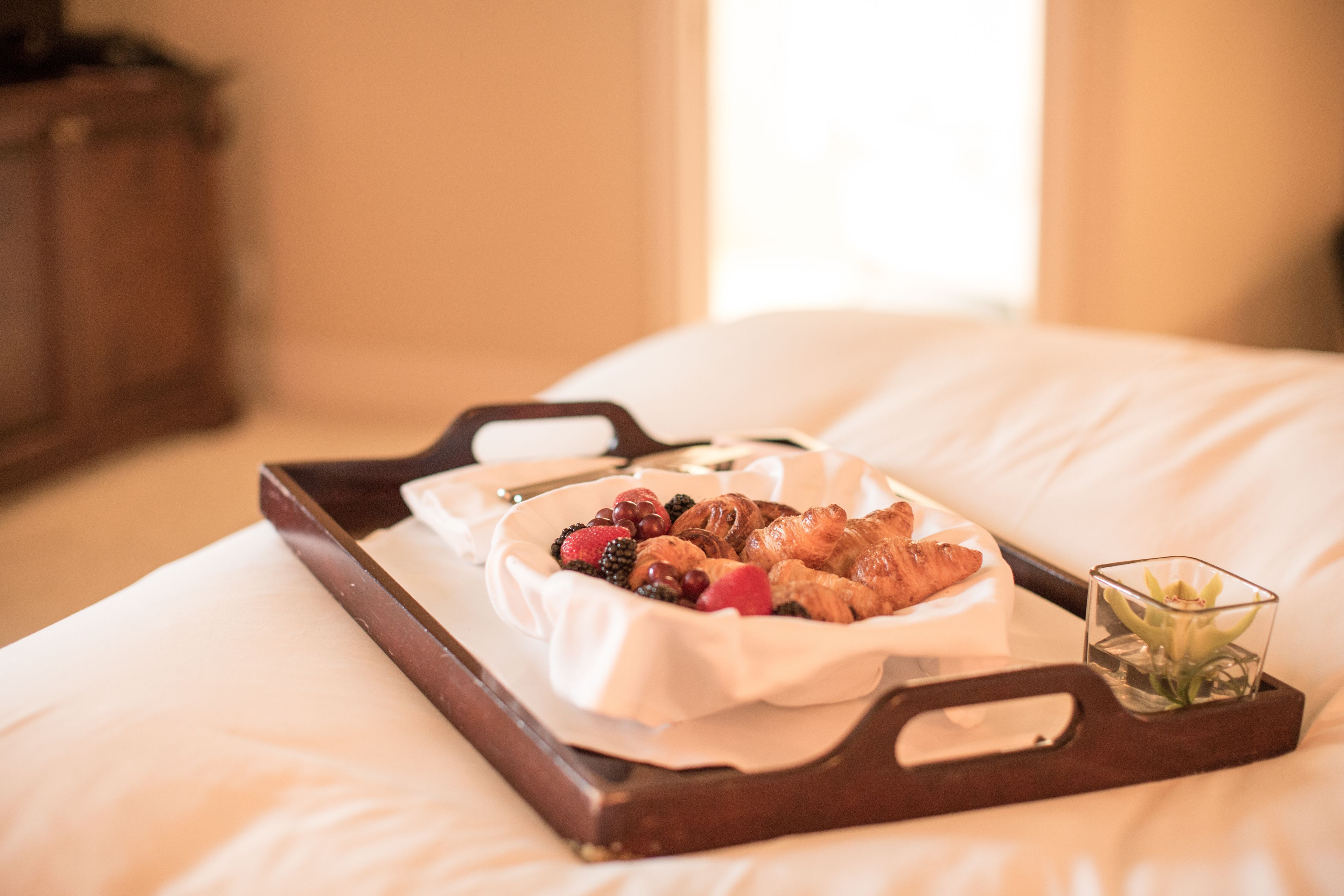 Un plateau avec des pâtisseries et des fruits rouges, disposés sur un lit.
