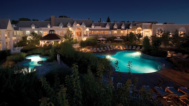 A large resort with multiple swimming pools, a well-lit outdoor area, and a grand building with multiple levels and balconies. - Hotel Le Bonne Entente (Québec City)