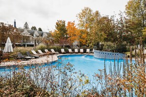Una piscina al aire libre de temporada, sombrillas