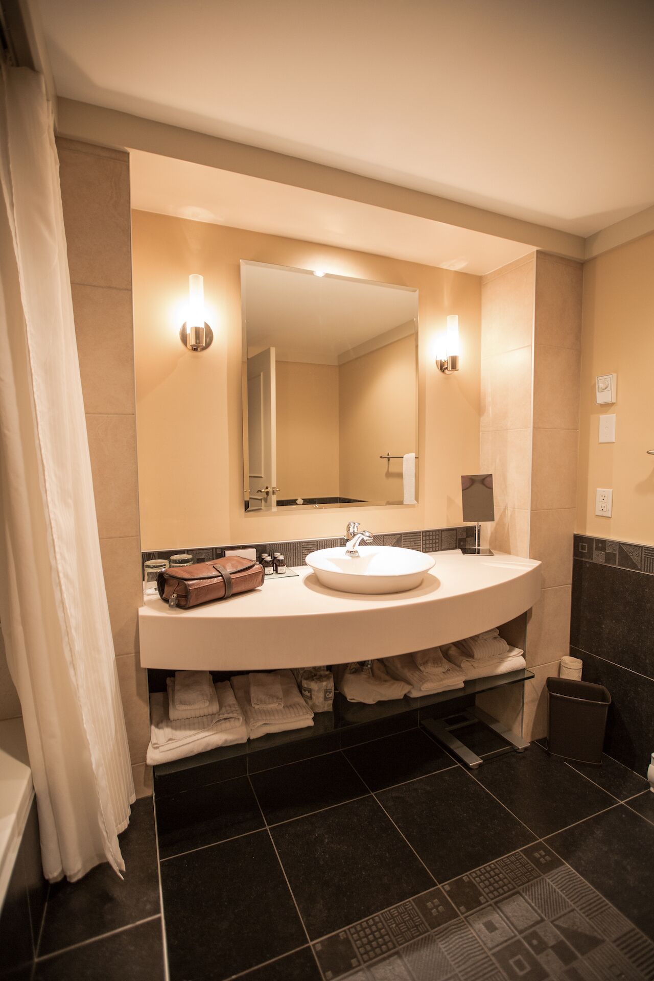 Un baño con lavamanos blanco, un espejo y dos luces empotradas.