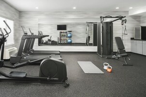 Un gimnasio moderno para el hogar con cintas de correr, un banco de pesas y equipamiento de ejercicio.