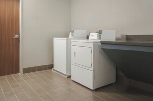 Un lavadero con lavadora y secadora Whirlpool, una encimera y una puerta.