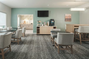 Habitación de hotel con kitchenette, televisor de pantalla plana y zona de estar con sillas y mesa.