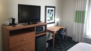 A hotel room with a bed, a desk with a chair, a television, a microwave, a small refrigerator, a trash bin, and a window with curtains. - City Express By Marriott Shepherdsville Louisville (Louisville)
