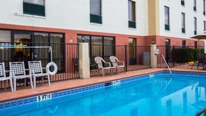 A swimming pool with lounge chairs and a fence.