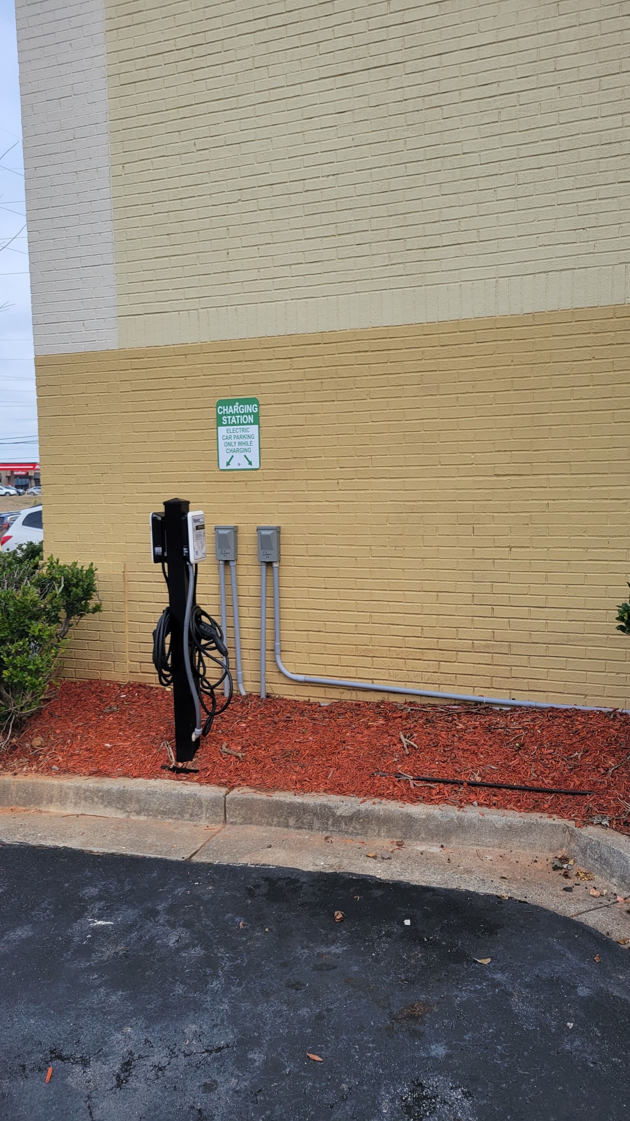 A charging station for electric cars with a sign indicating it is for electric car parking only while charging.