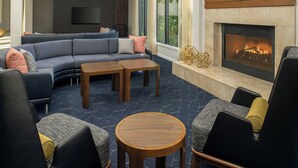 Una sala de estar moderna con un sofá modular, dos mesitas de madera y una chimenea.