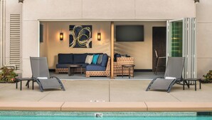 Zona junto a la piscina con sofá, sillas y una mesa.