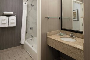 Un baño moderno con bañera, cabina de ducha de vidrio, lavabo con encimera de granito y un espejo grande.