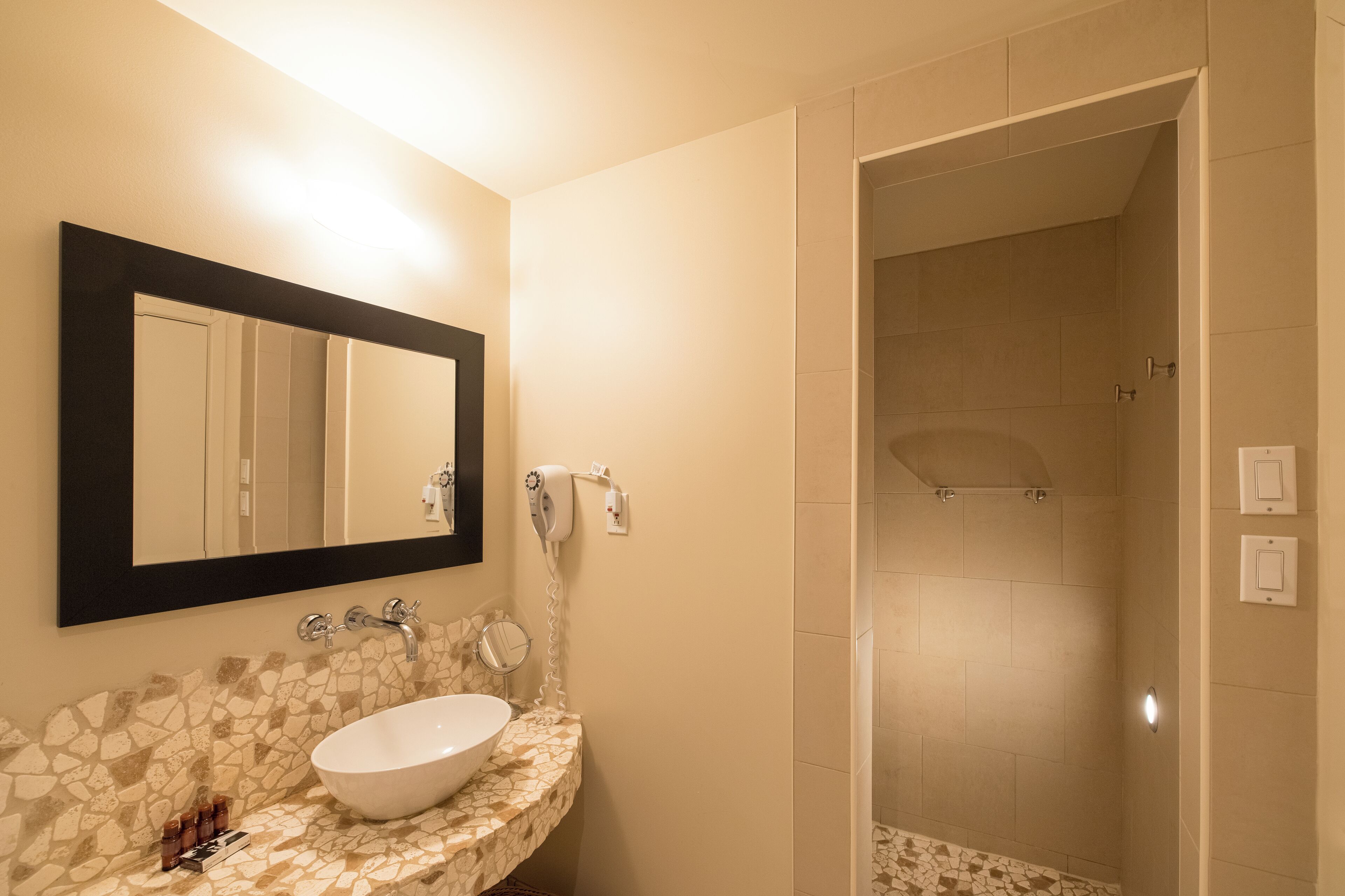 Une salle de bain avec un lavabo blanc, un miroir et un espace douche.
