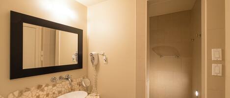 Une salle de bain avec un lavabo blanc, un miroir et un espace douche.