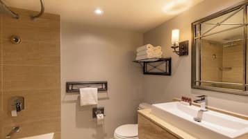 Un baño moderno con bañera, inodoro, lavamanos y un espejo grande.