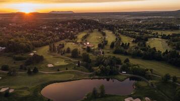 Enjoy a round of golf amidst lush trees, sand bunkers, and water hazards, with local amenities nearby.
