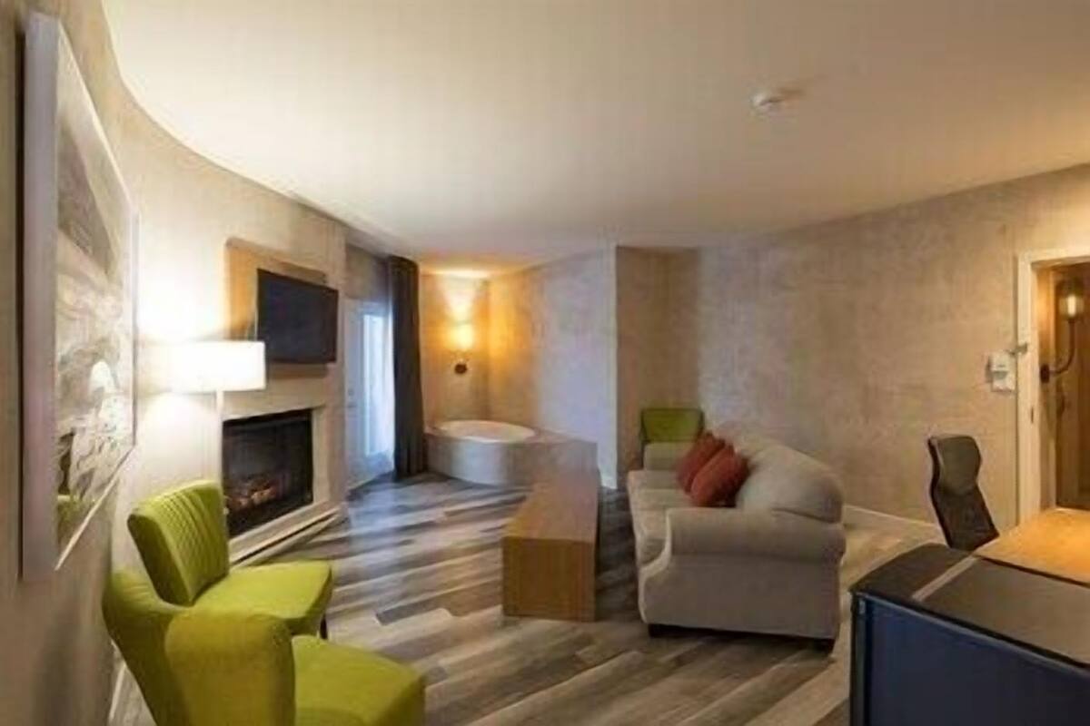 A modern living room with a fireplace, a sofa, a green armchair, and a small table.