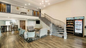 A spacious living area with a staircase, a bar area, and a refrigerator stocked with beverages.