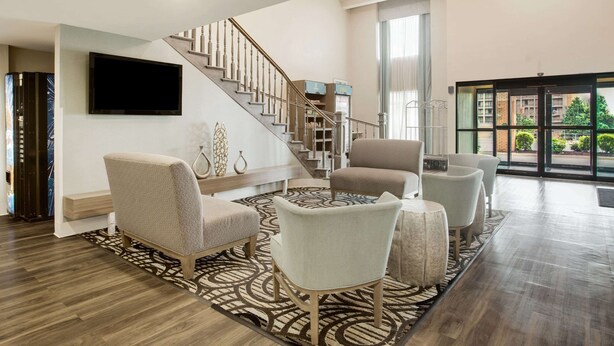 A spacious living area with a staircase, comfortable seating, a flat-screen TV, and a large window offering a view of the outdoors.