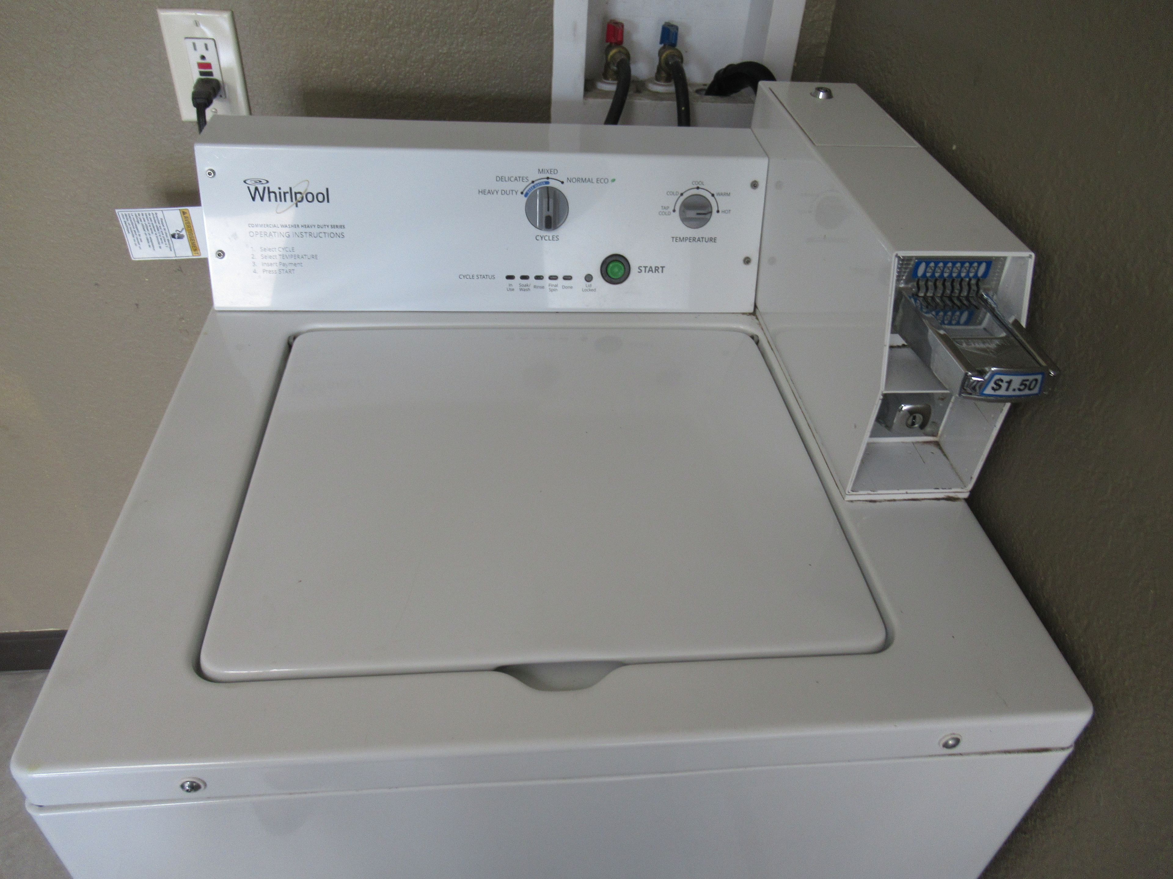 A Whirlpool commercial washer with a control panel, a water inlet, and a coin slot for payment.