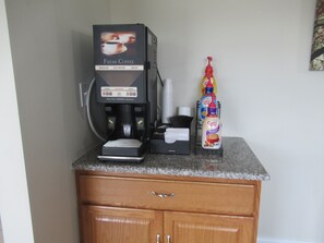 A coffee machine with a 'Fresh Coffee' label, a bottle of coffee creamer, and a coffee mug on a countertop.