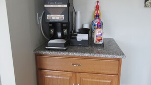 Máquina de café em bancada, com leite condensado e uma caneca.