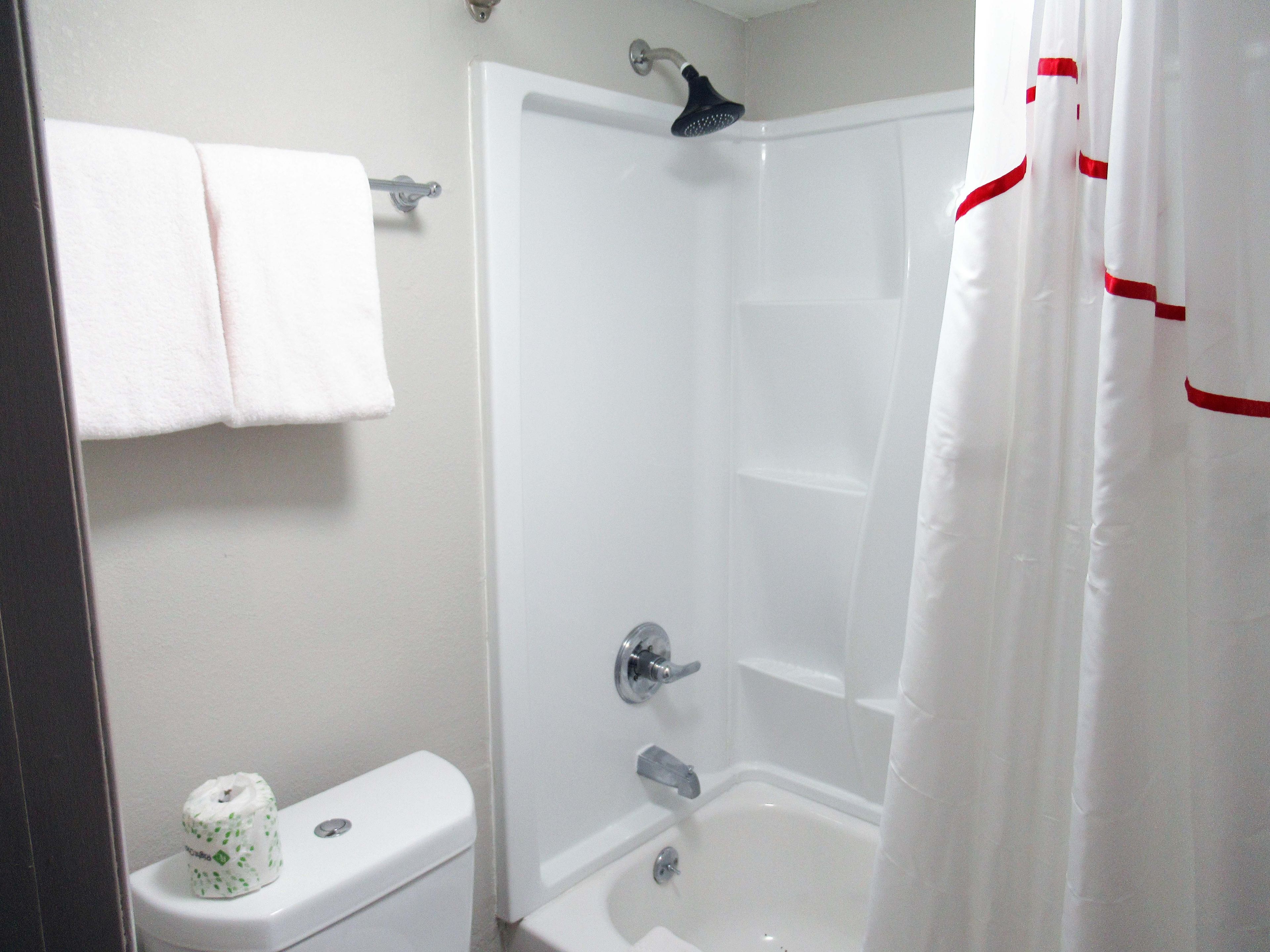 A bathroom with a shower, toilet, and a towel rack.