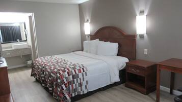 A hotel room with a bed, bedside table, and a window with curtains.