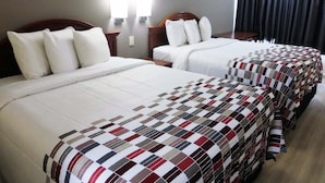 A hotel room with two beds, a nightstand, and a window with curtains.