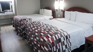 Quarto de hotel com duas camas, banheiro e janela com cortinas.
