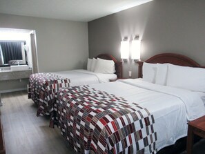 Quarto de hotel com duas camas, banheiro e janela com cortinas.