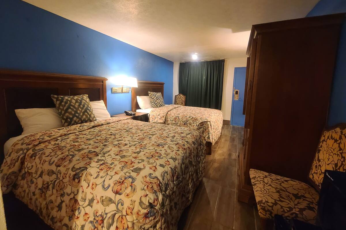 Habitación de hotel con dos camas, una mesita de noche, una silla y una puerta.