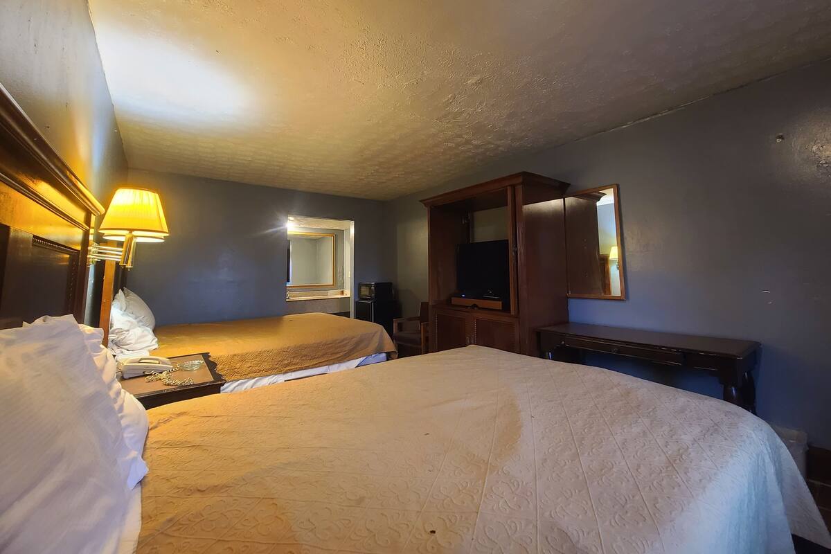 Habitación de hotel con dos camas, un escritorio, un televisor y un espejo.