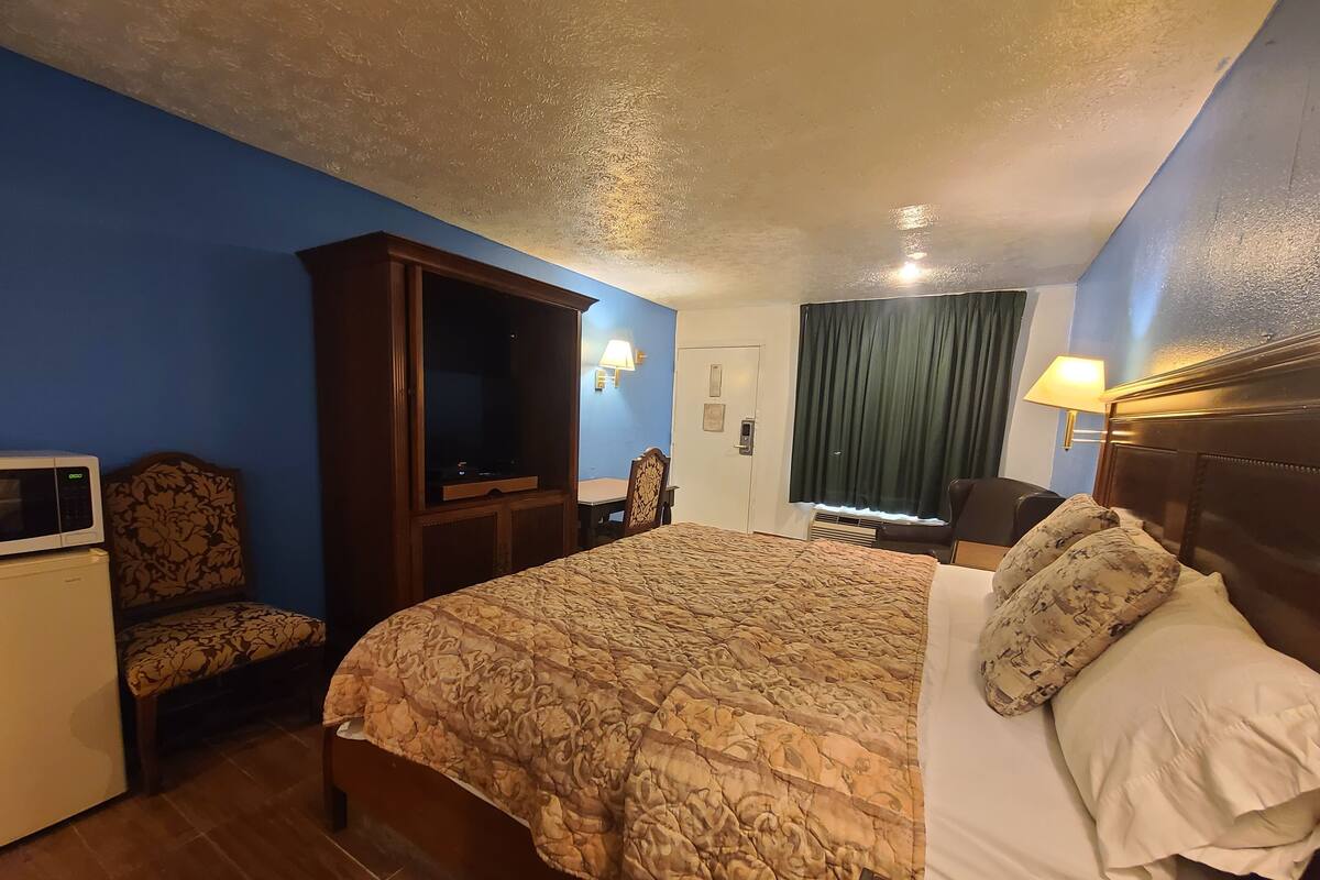 Una habitación de hotel con una cama, televisor, escritorio y una silla.