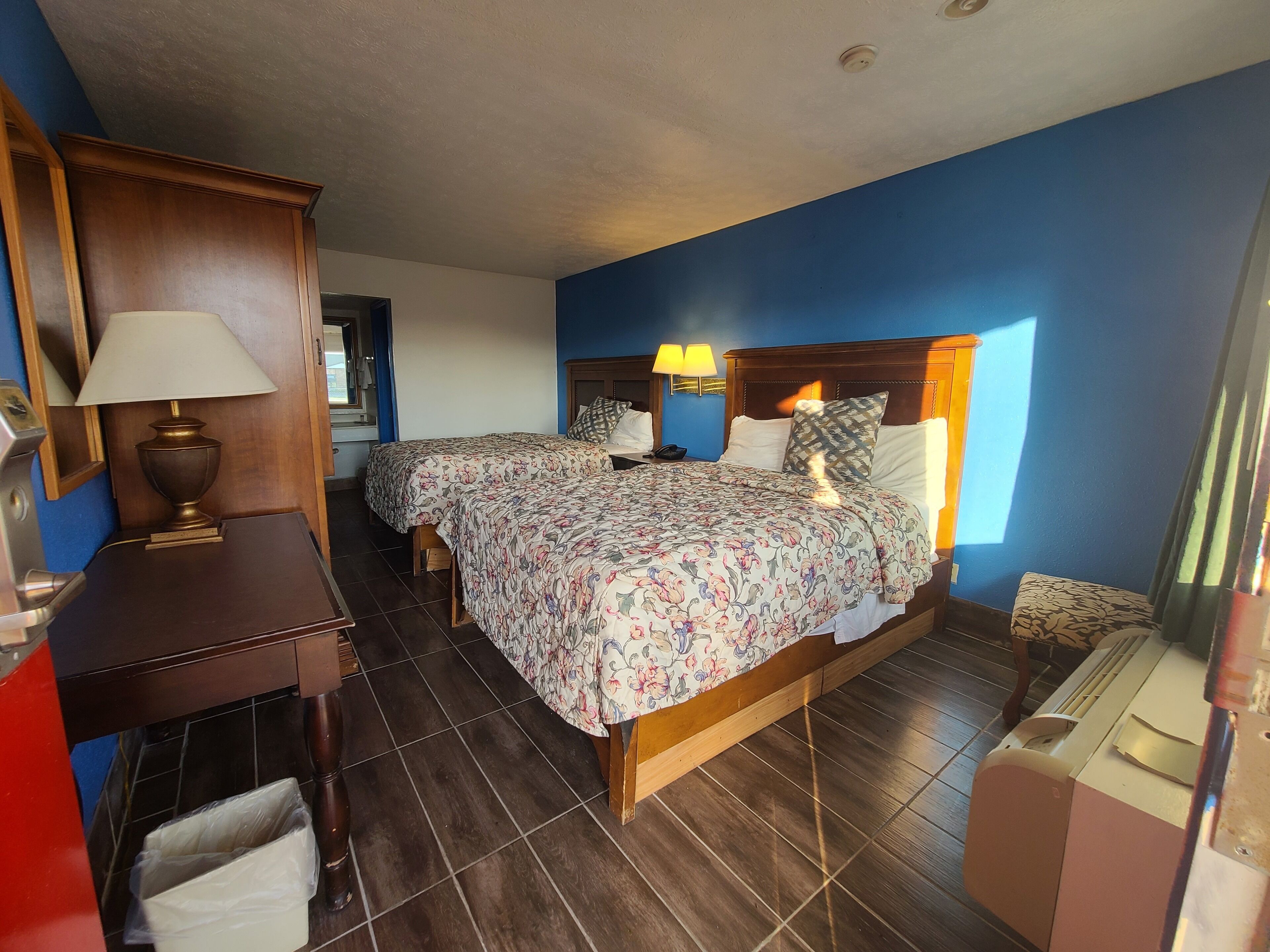 Een hotelkamer met twee bedden, een bureau, een lamp en een telefoon.