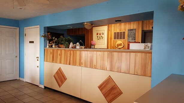 A reception area with a wooden counter, a blue wall, and a door to the left.