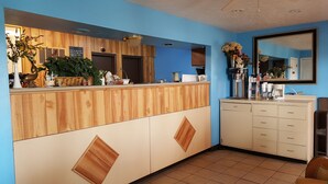A reception area with a wooden counter, a blue wall, a mirror, and a coffee machine.