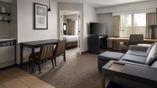 A modern hotel room with a dining area, a sofa, a TV, and a desk. - Residence Inn By Marriott Stockton (Stockton)