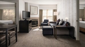 A modern hotel room with a flat-screen TV, a sofa, a desk, and a fireplace. - Residence Inn By Marriott Stockton (Stockton)