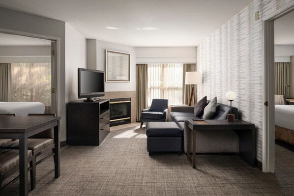 Een moderne hotelkamer met een flatscreen televisie, een bank, een bureau en een open haard.