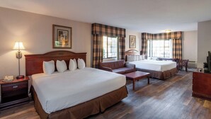 A hotel room with two beds, a sofa, a desk, a lamp, and a television. - Studio City Court Yard Hotel (Studio City)